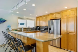 A modern kitchen with wooden cabinets, stainless steel appliances, and a large island with bar stools.