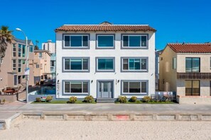 A modern two-story building with a tiled roof, large windows, and a front entrance.