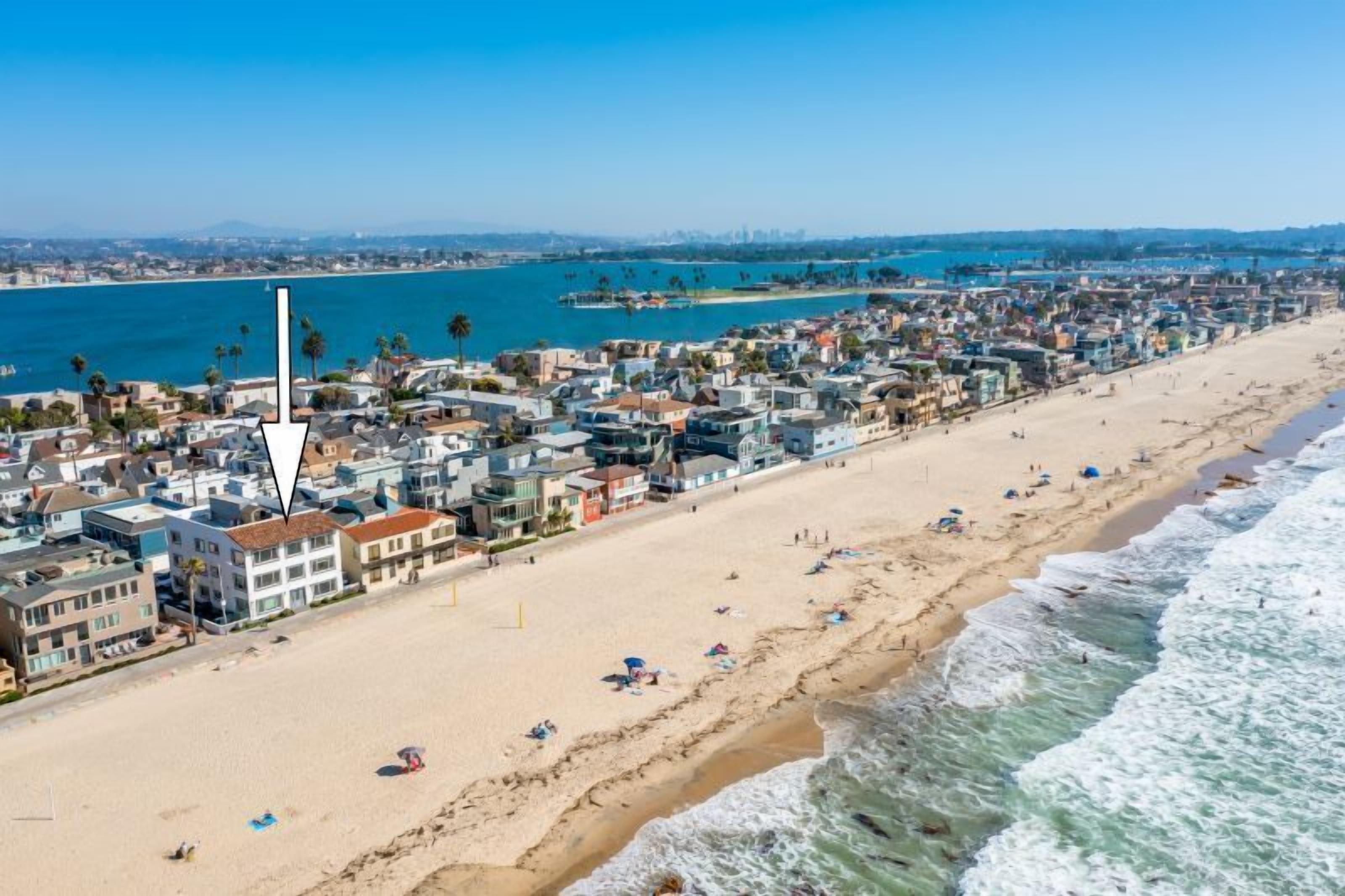 Un paysage urbain côtier avec une plage, des bâtiments et un ciel dégagé.