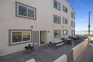 En byggnad med flera våningar som har en uteplats med sittplatser och utsikt över stranden.