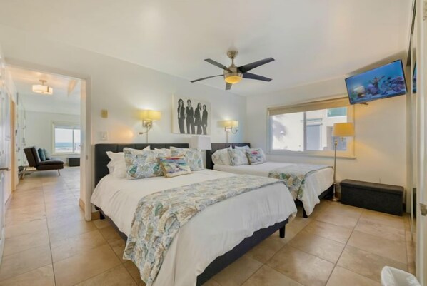A hotel room with two beds, a ceiling fan, wall-mounted lamps, a TV, and a large window. - Right on the Famous Mission Beach Boardwalk - Sleeps up to 10 on Ground Floor - Best location in Mission Beach (San Diego)