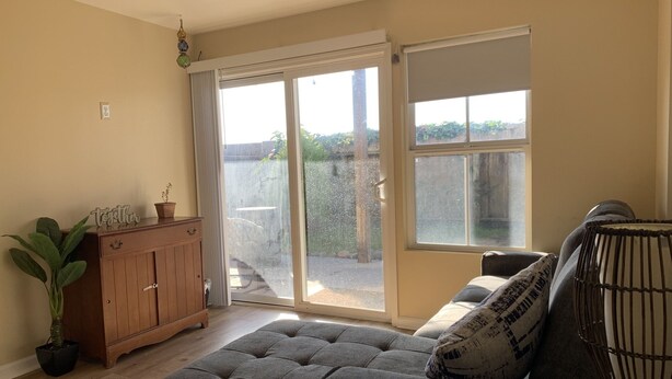 Ein Wohnzimmer mit grauem Sofa, einer Holzkabine und einer großen Schiebeglasdoor zum Patio.