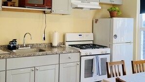 Eine moderne Küche mit grauen Schränken, einer Edelstahl-Spüle, einem Gasherd und einem weißen Kühlschrank.