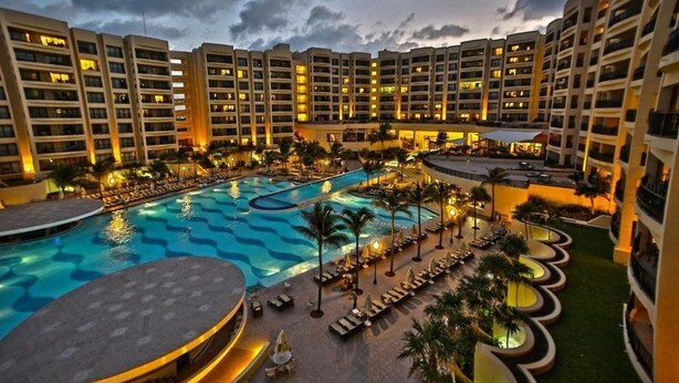 Un hotel con varias torres altas, una piscina grande y zonas de estar al aire libre.