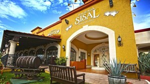 Un edificio con fachada amarilla, arcos y un letrero que dice 'Hacienda Sisal Mexican Grill'.
