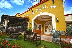 Ein Gebäude mit gelber Fassade, Bögen und einem Schild, auf dem 'Hacienda Sisal Mexican Grill' steht.