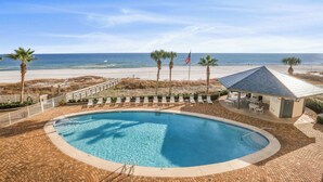 A pool area with a view of the beach, palm trees, and a flag. - Windward Pointe 1401 : Beachfront Corner Condo w/ Wrap-Around Gulf Views (Orange Beach)