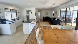 Une cuisine moderne avec un îlot central, un coin repas doté d’une table en bois et un salon avec un canapé noir.