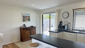 Une cuisine moderne avec un plan de travail noir, des armoires blanches et un tabouret en bois.