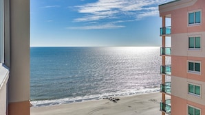 A view of a beach from a balcony with a clear sky and ocean. - Light and Spacious Corner Unit, Ocean View, Pools | Crescent Keyes - PH 10 (North Myrtle Beach)