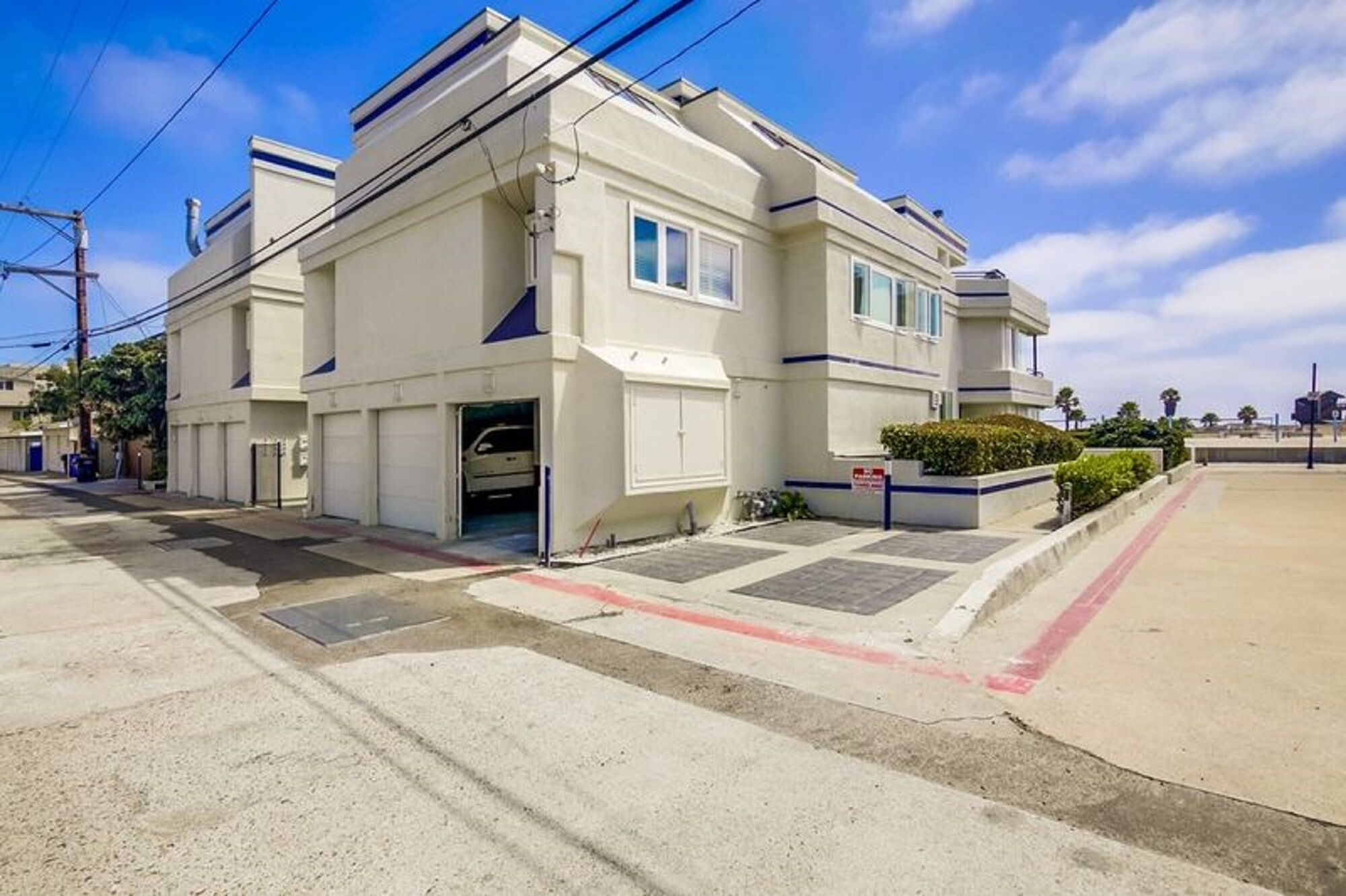 A two-story building with a garage entrance, a small front garden, and a clear sky.