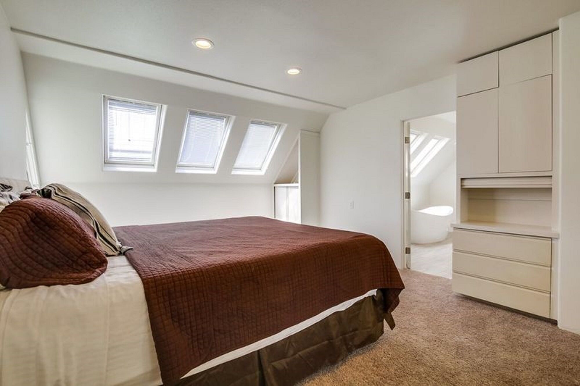 A bedroom with a bed, a wardrobe, and skylights.