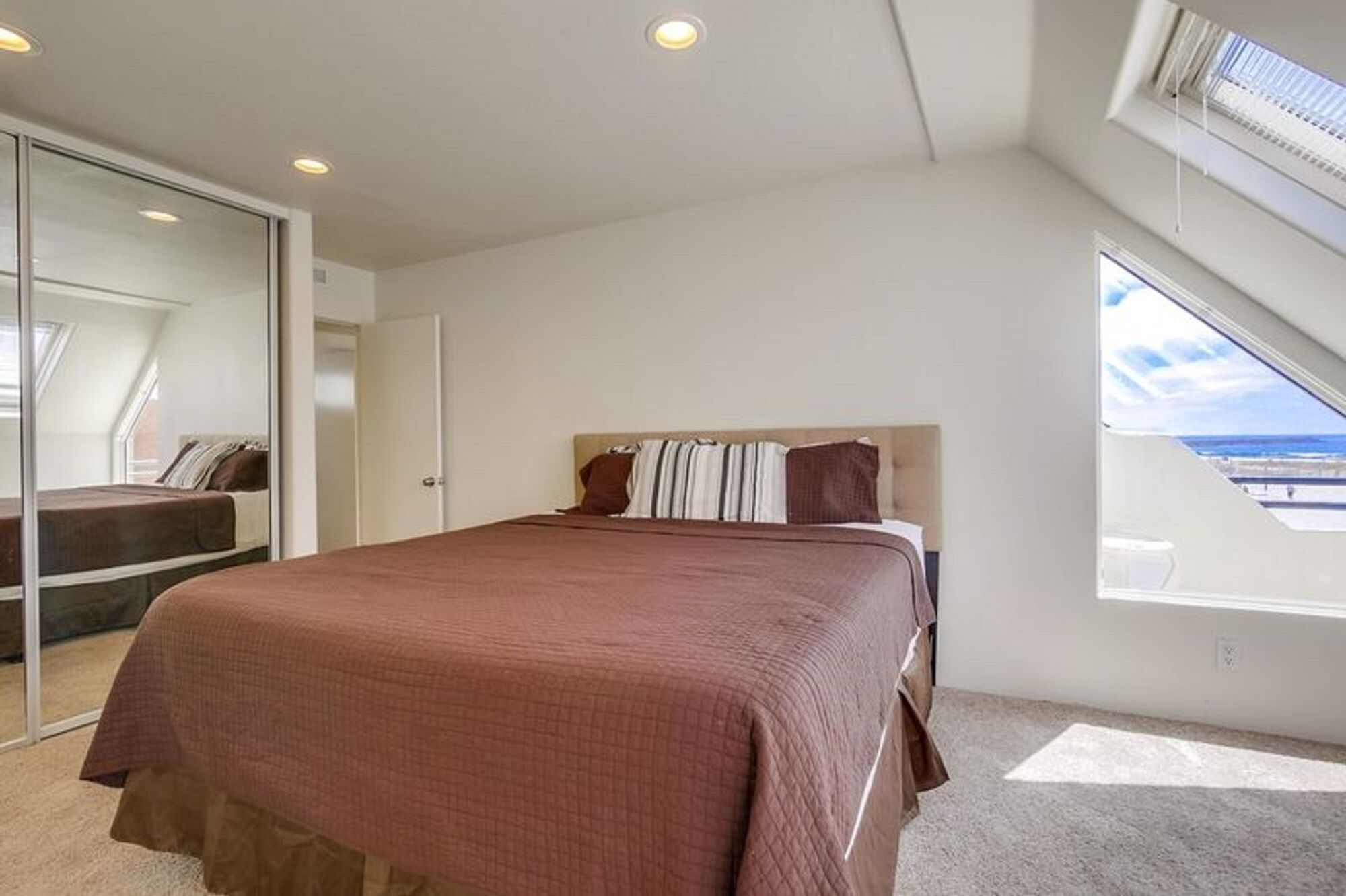 Une chambre à coucher avec un grand lit, une armoire et une fenêtre donnant sur un beau paysage.