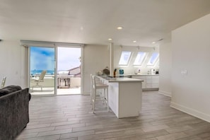 A modern kitchen with a central island, a dining area with chairs, and a sliding glass door leading to an outdoor space.