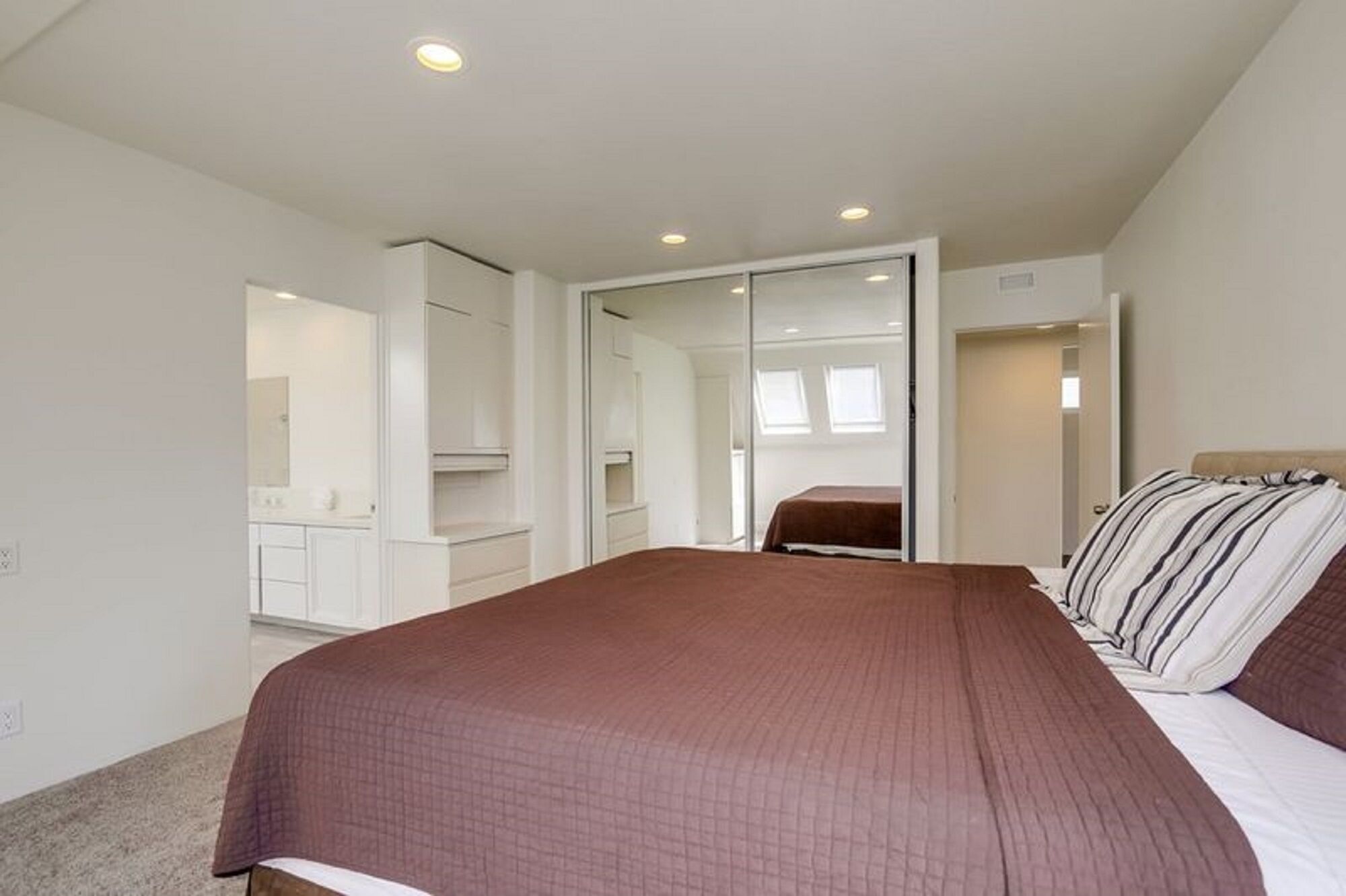 A bedroom with a large bed, a wardrobe, and a mirror.