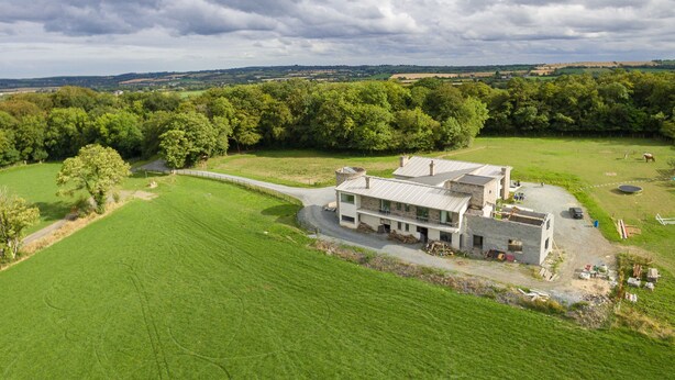 A large, modern house with a spacious lawn, surrounded by dense trees and open fields. - Rathescar Grove (Dunleer)