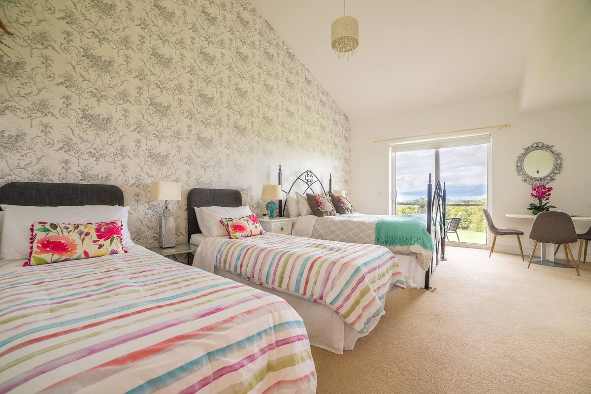 A bedroom with two beds, a desk, and a chair.
