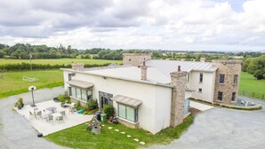 A modern two-story house with a stone facade, large windows, and a patio area with outdoor furniture. - Rathescar Grove (Dunleer)