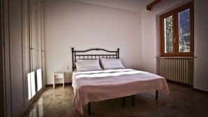 A bedroom with a bed, a nightstand, a window, and a radiator. - VICTORY HOUSE 4 FRONT LAKE AP3 GARDEN & SPA (Colmegna)