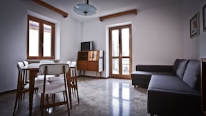 A living room with a dining area, a sofa, a TV on a wooden cabinet, and large windows. - VICTORY HOUSE 4 FRONT LAKE AP3 GARDEN & SPA (Colmegna)