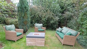 Un espacio al aire libre con mobiliario de mimbre y cojines verdes.