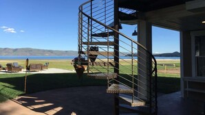 Escadaria em espiral que leva a uma varanda com vista panorâmica de um lago e montanhas.