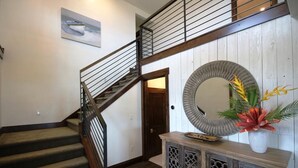 Uma escadaria com guarda-corpo de madeira e corrimão de metal, que leva a um andar superior.