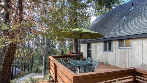 A wooden deck with outdoor furniture, a table, and an umbrella.