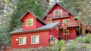 A red cabin with a balcony and a staircase leading to an upper level.