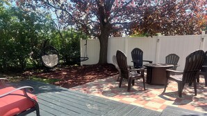 Eine Terrasse im Freien mit Tisch und Stühlen, umgeben von einer Holzterrasse und einem weißen Zaun.