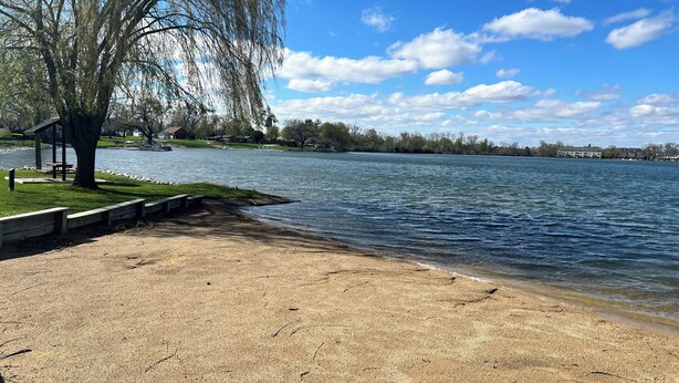 Ein Park am Seeufer mit einer Bank, einem Picknicktisch und einem Kiosk.
