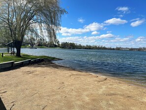 Un parc au bord du lac, avec un banc, une table de pique-nique et un kiosque.