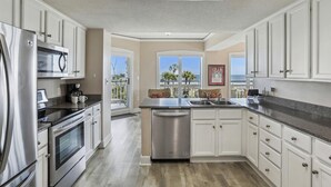 A modern kitchen with stainless steel appliances, white cabinetry, and a view to the outdoors. - Direct Ocean Front End Villa w/ Screened Balcony (Hilton Head Island)