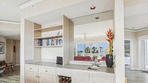 A modern kitchen with built-in shelves, a wine rack, and a view of the outdoors. - Direct Ocean Front End Villa w/ Screened Balcony (Hilton Head Island)