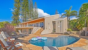 A modern house with a swimming pool, lounge chairs, and a deck area.