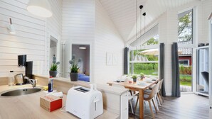 Una cocina moderna con un gran ventanal, un comedor y un fregadero con cafetera.