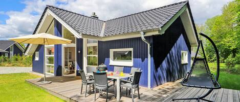 A modern house with a deck, a dining area, and a garden.