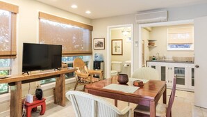 A cozy living room with a TV, dining table, and chairs. A kitchen is visible in the background. - Loft In Kailua - Spacious with Parking, Internet and minutes to Kailua Beach! (Kailua)