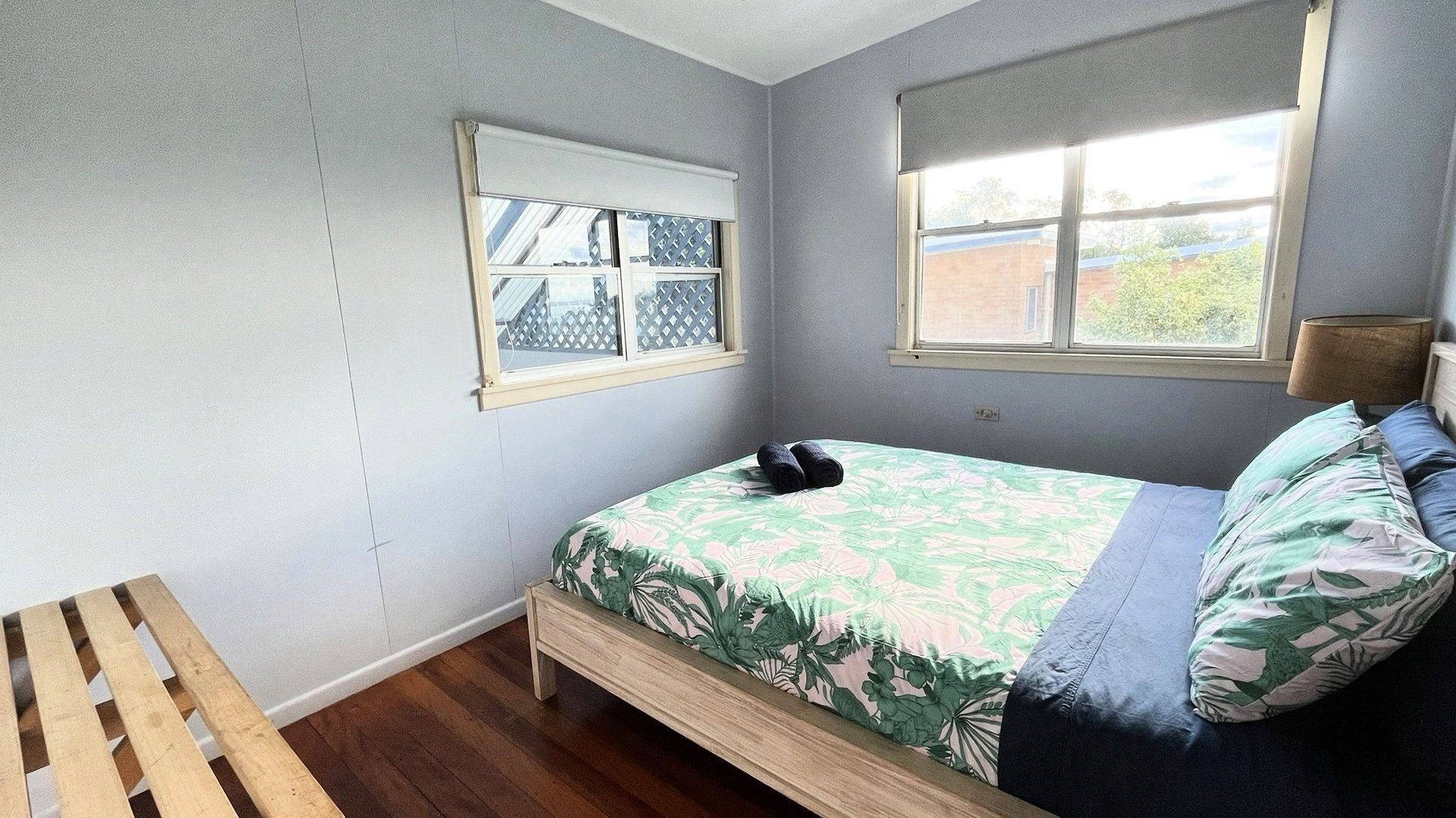 Une chambre à coucher avec un lit, un banc en bois et deux fenêtres.