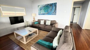 A living room with a sofa, a coffee table, a TV, and a painting on the wall.