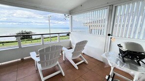 Ein Balkon mit zwei weißen Stühlen, einem Tisch und einem Helm auf dem Tisch.