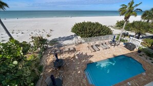A poolside area with lounge chairs and a view of the beach.