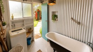 Casa de banho com banheira independente, janela com vidro jateado e porta para área exterior.