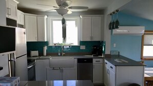 A kitchen with white cabinets, a central island, a ceiling fan, and a window providing natural light.