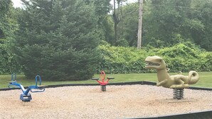 A playground with seesaws and a dinosaur-shaped swing set.