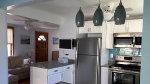 A modern kitchen with white cabinets, stainless steel appliances, and pendant lighting.
