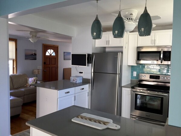 A modern kitchen with white cabinets, stainless steel appliances, and pendant lighting.