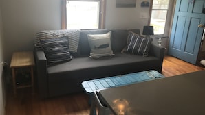 A living room with a sofa, pillows, a small table, and a door.