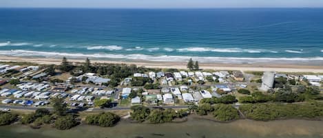 An aerial view of a coastal residential area with houses, a beach, and a marina.