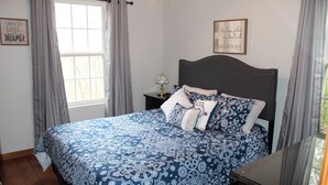 Une chambre à coucher avec un grand lit, une table de chevet, une lampe et deux éléments de décoration murale.